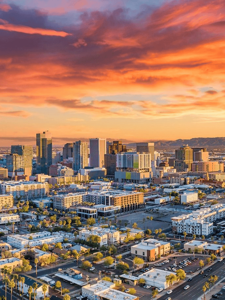 Vibrant city skyline during sunset with modern buildings and colorful sky, showcasing urban development and scenic views.