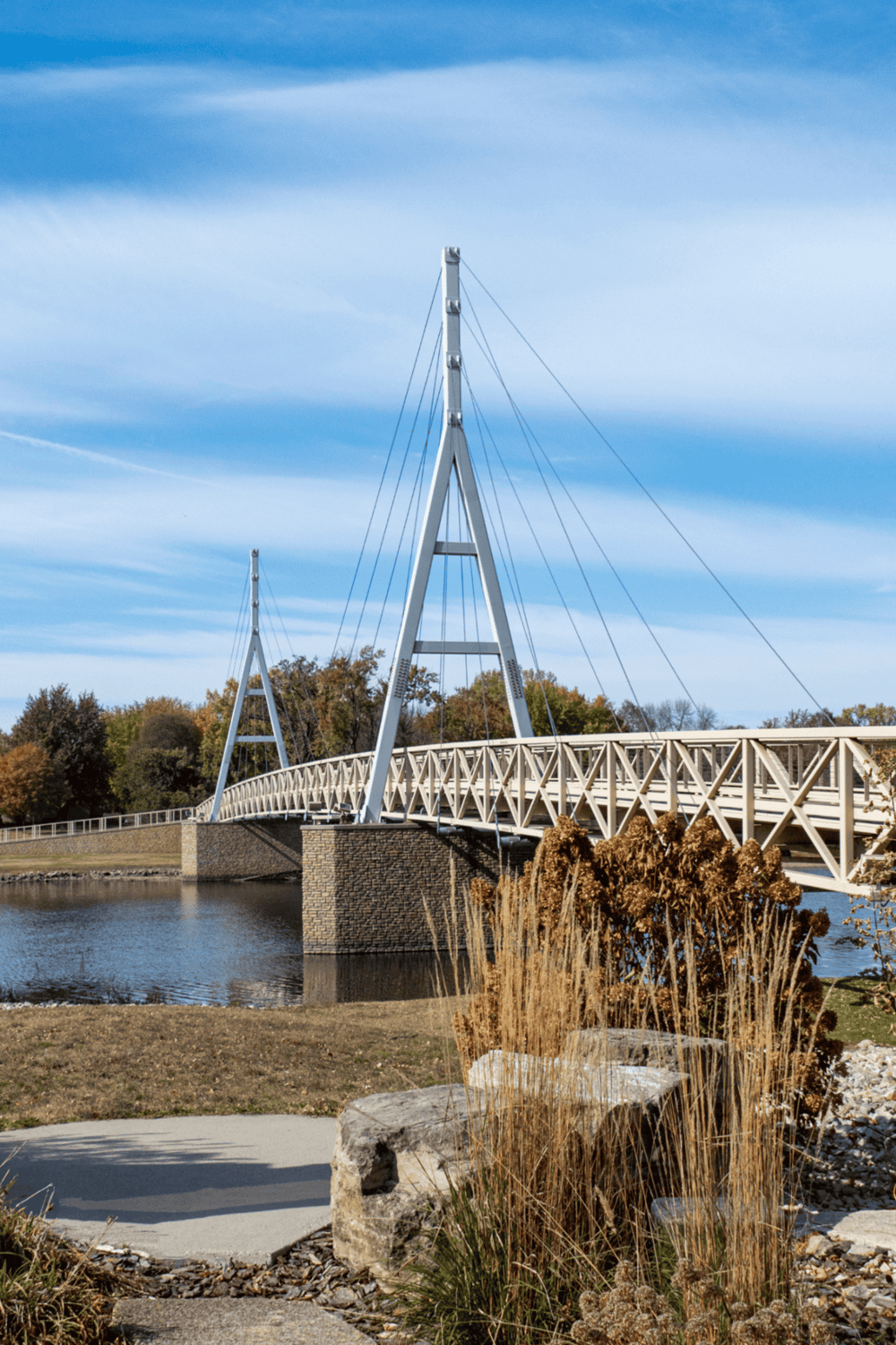 1. Modern cable-stayed bridge over water with scenic autumn trees in background.