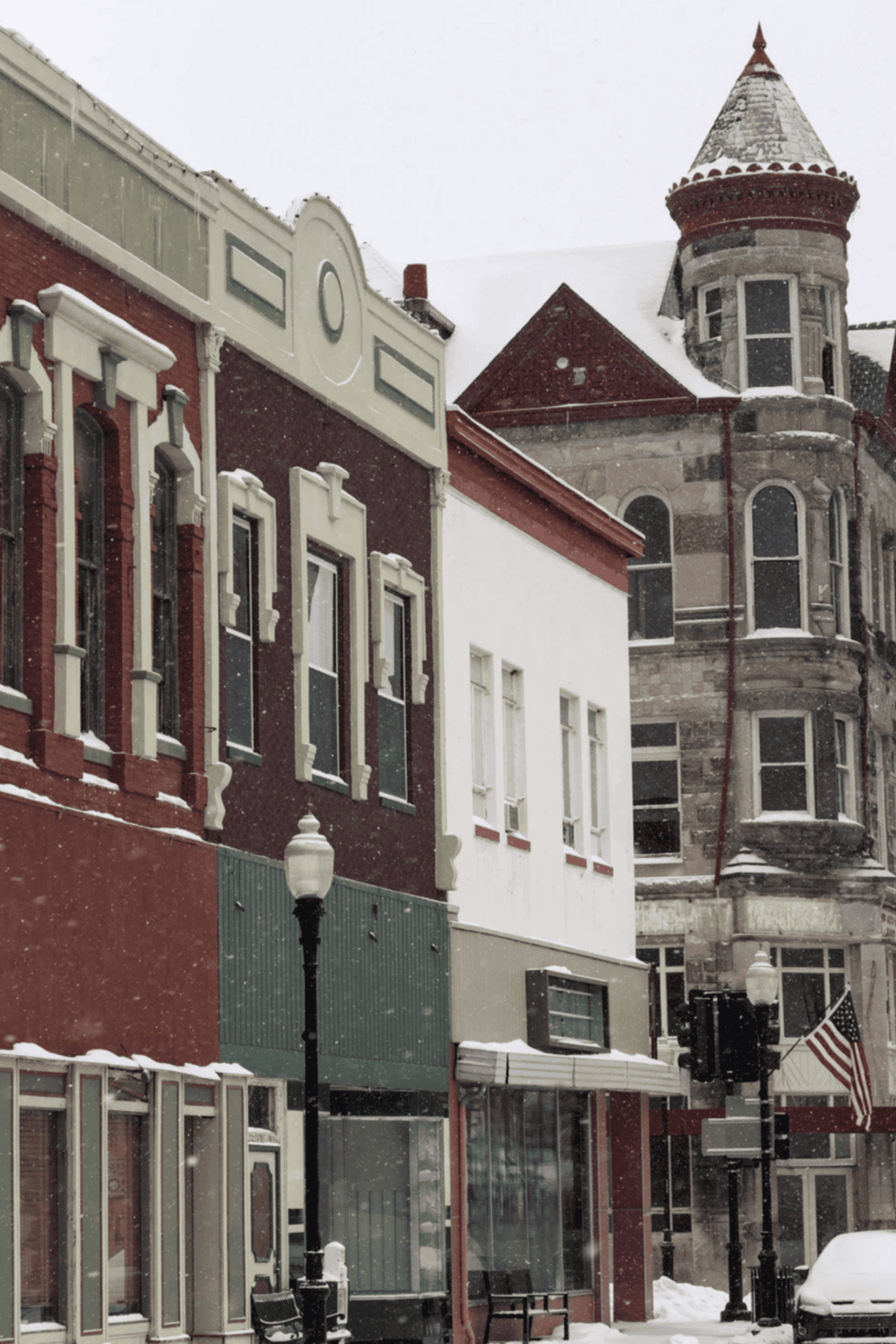 Colorful historic city buildings with snow-covered streets and American flag, showcasing architectural charm.
