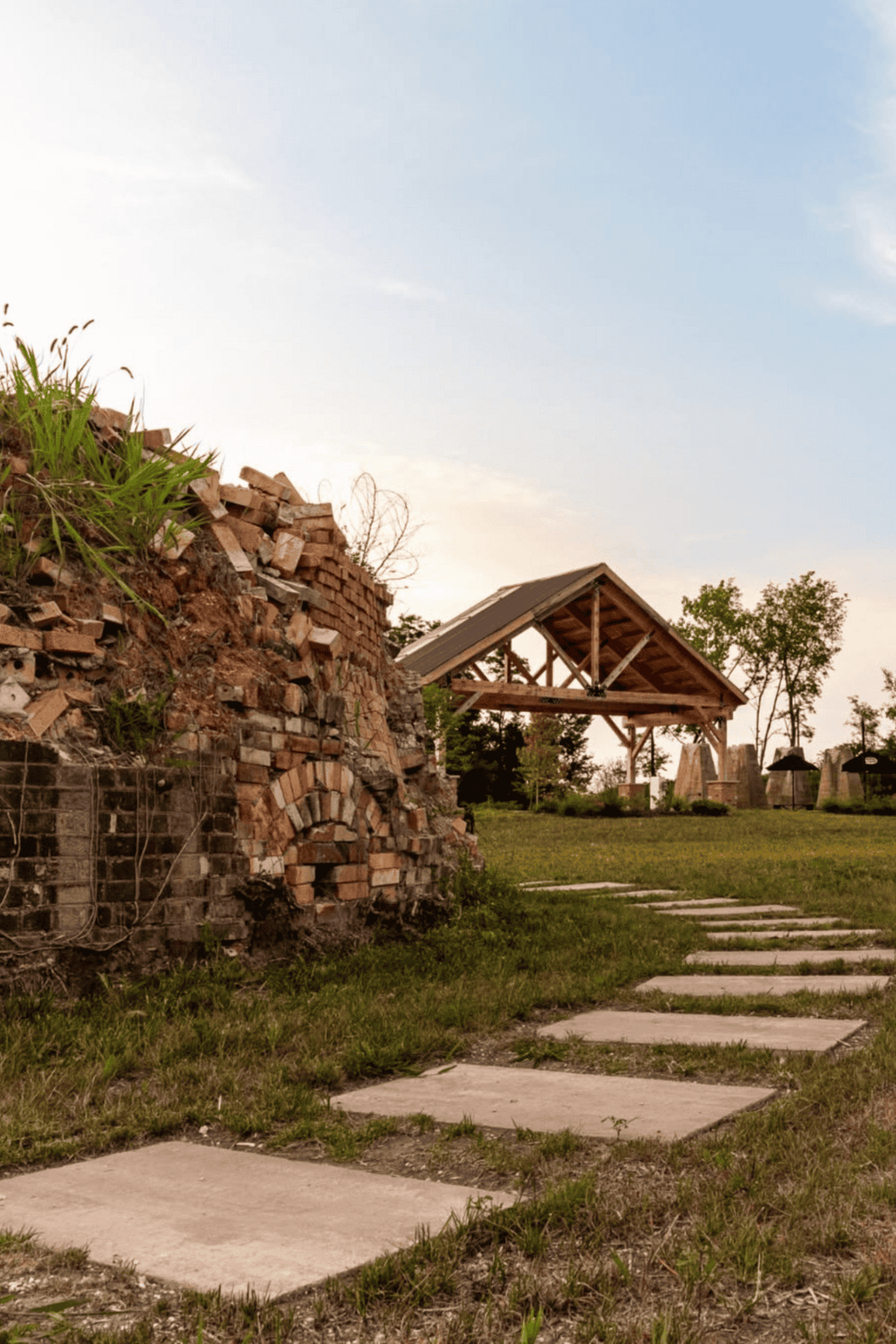 Rustic brick wall and wooden pavilion at QuestForDirections outdoor venue, scenic landscape, outdoor event location, natural setting.