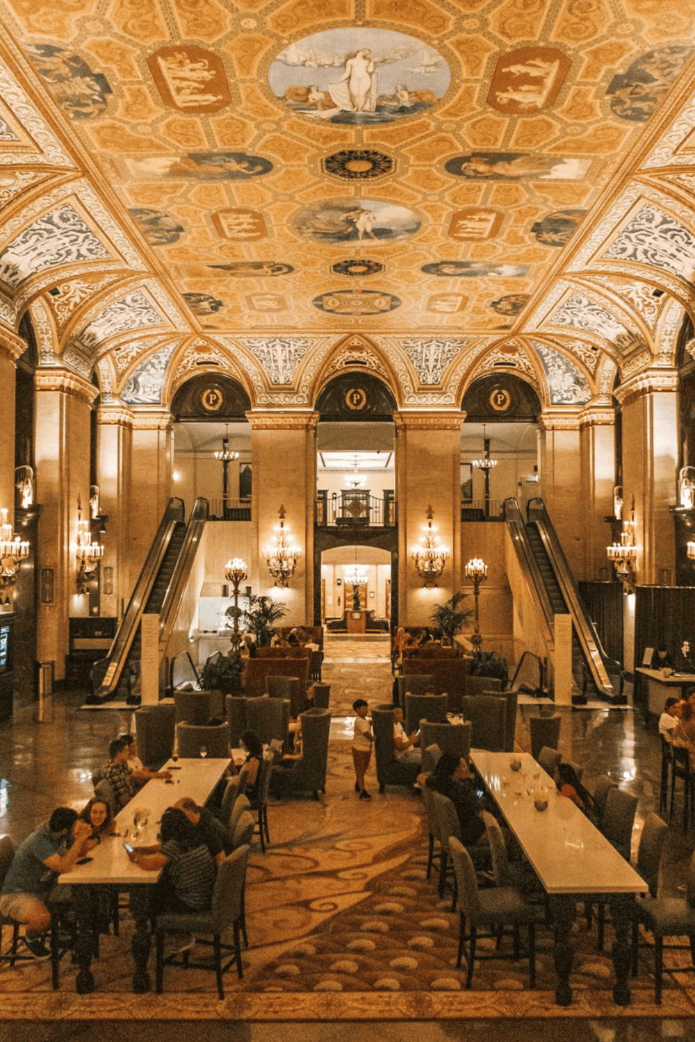Grand hotel lobby with ornate ceiling, chandeliers, and elegant decor, capturing luxurious hospitality ambiance.