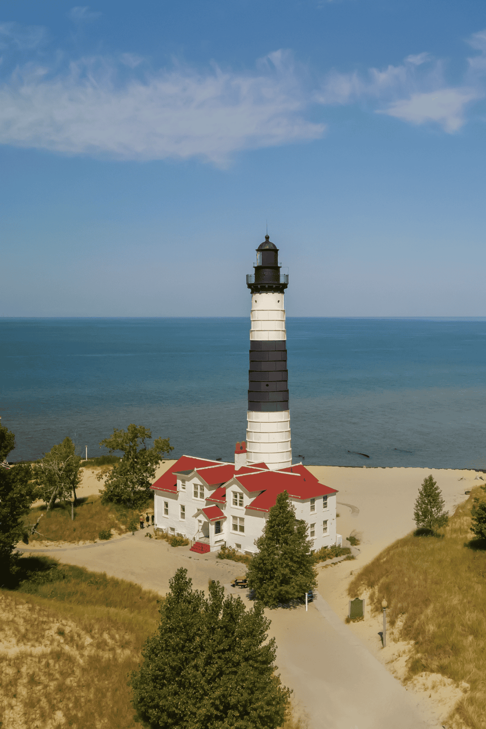Lighthouse on the coast with blue sky and ocean in the background, scenic seaside view for travel or navigation guides.