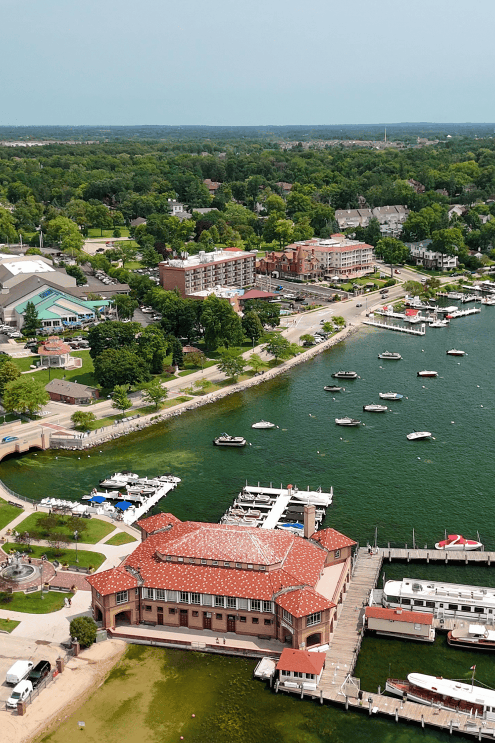 1. Aerial view of lakeside town with boats, marina, and lush green surroundings.
