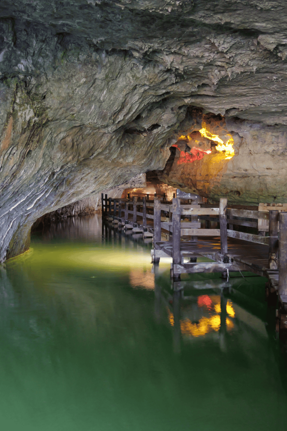 1. Underground cave with wooden walkway and colorful lighting, adventure hiking attraction.