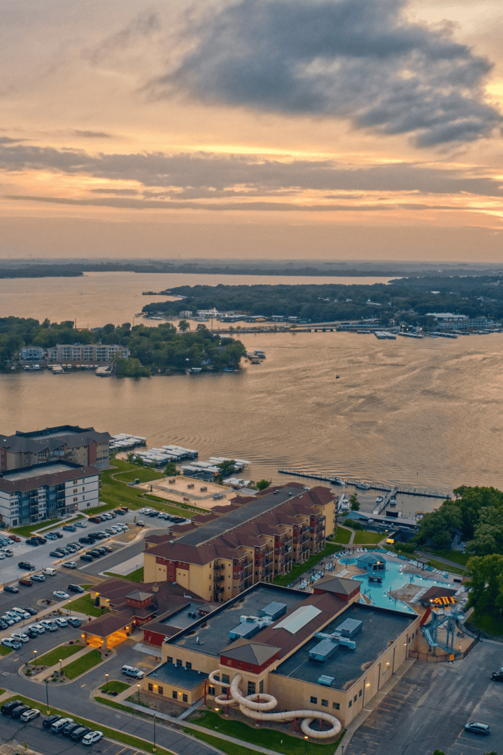 Panoramic view of lakeside resort with water park, marina, and sunset scenery for outdoor activities and relaxation.