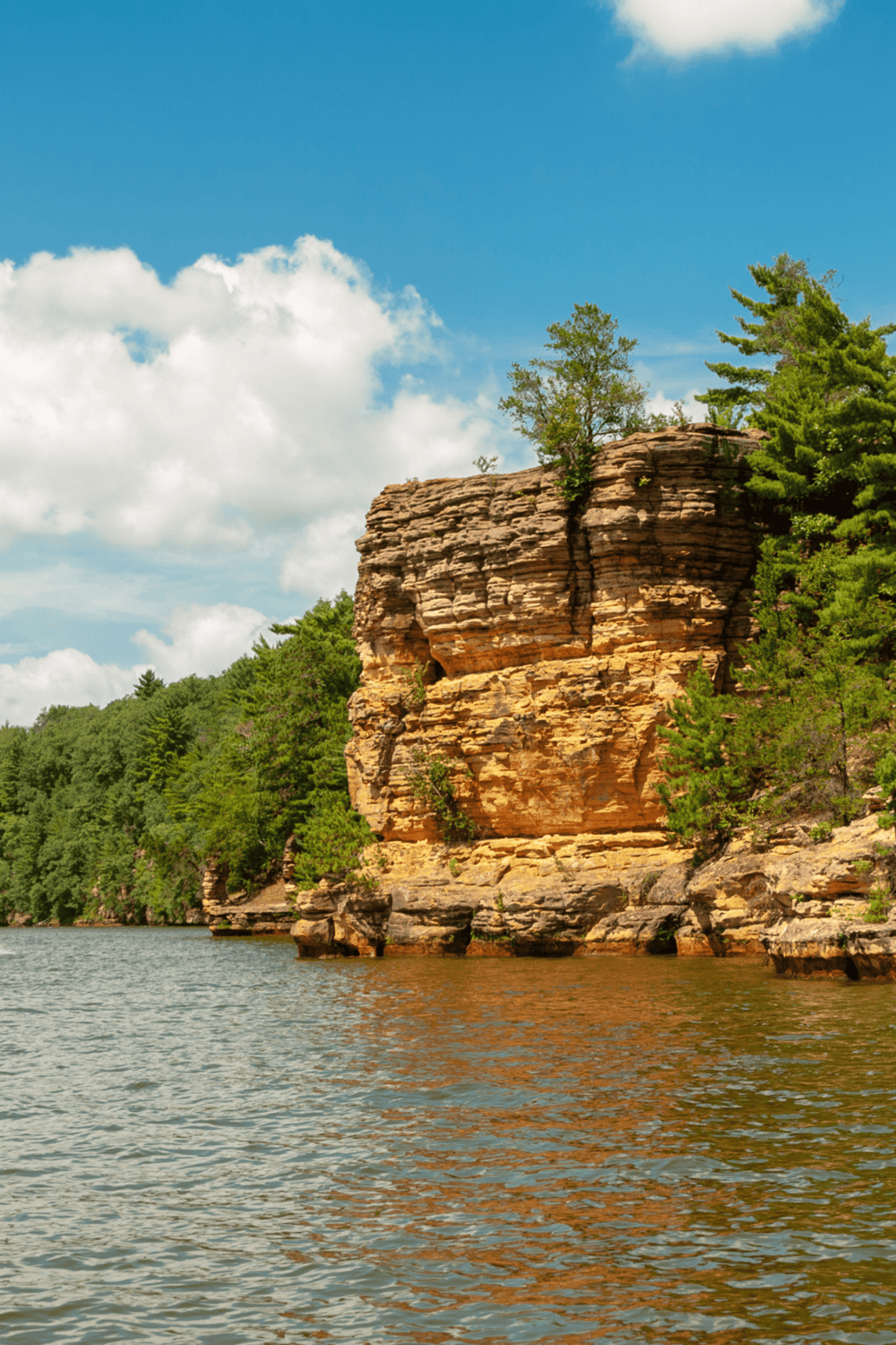Cliffside landscape at Lake of the Ozarks with lush green trees and blue skies.