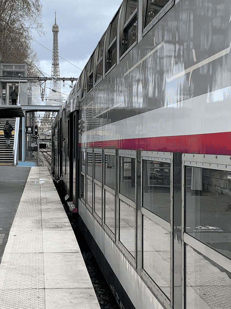 Modern double-decker train at Paris station with Eiffel Tower in background, public transit, travel, transportation, city commuting, QuestForDirections.
