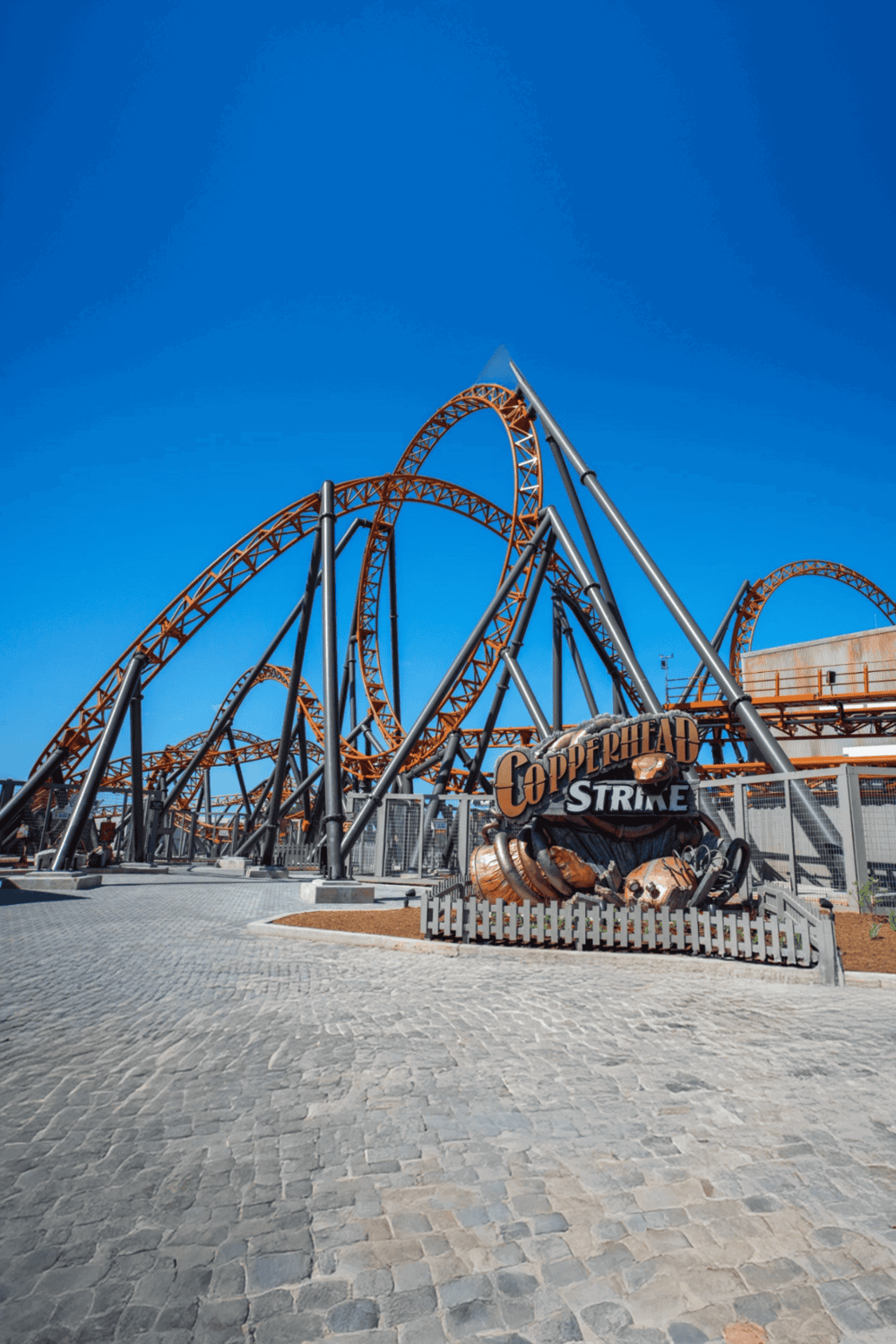 Thrilling roller coaster at Quest for Directions amusement park under a clear blue sky.
