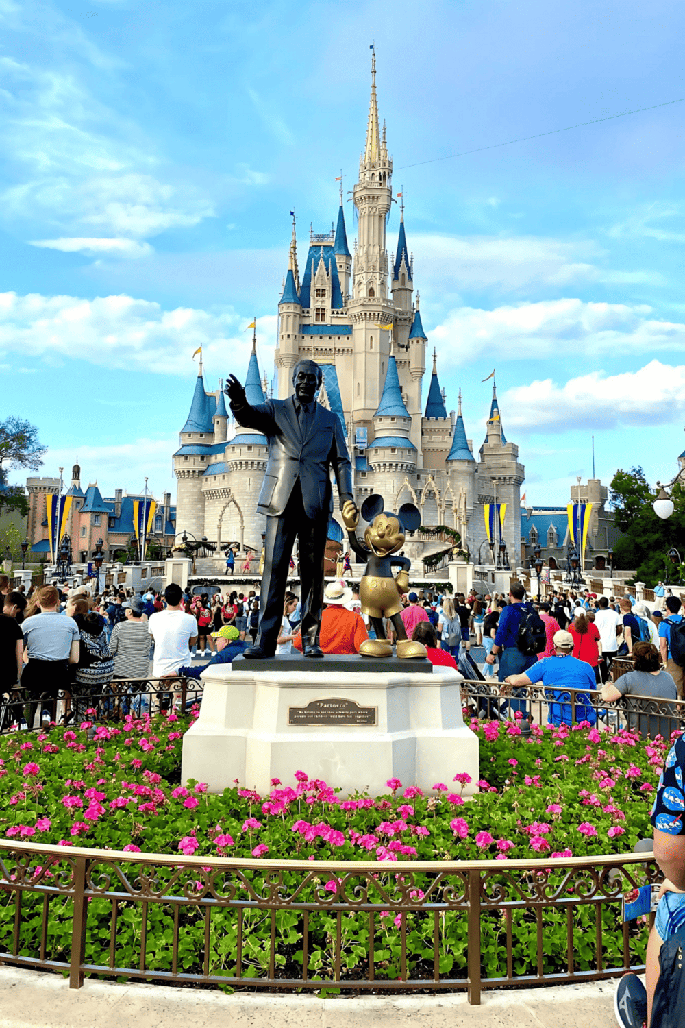 Disney castle with Walt Disney statue and Mickey Mouse, Disneyland theme park attraction.