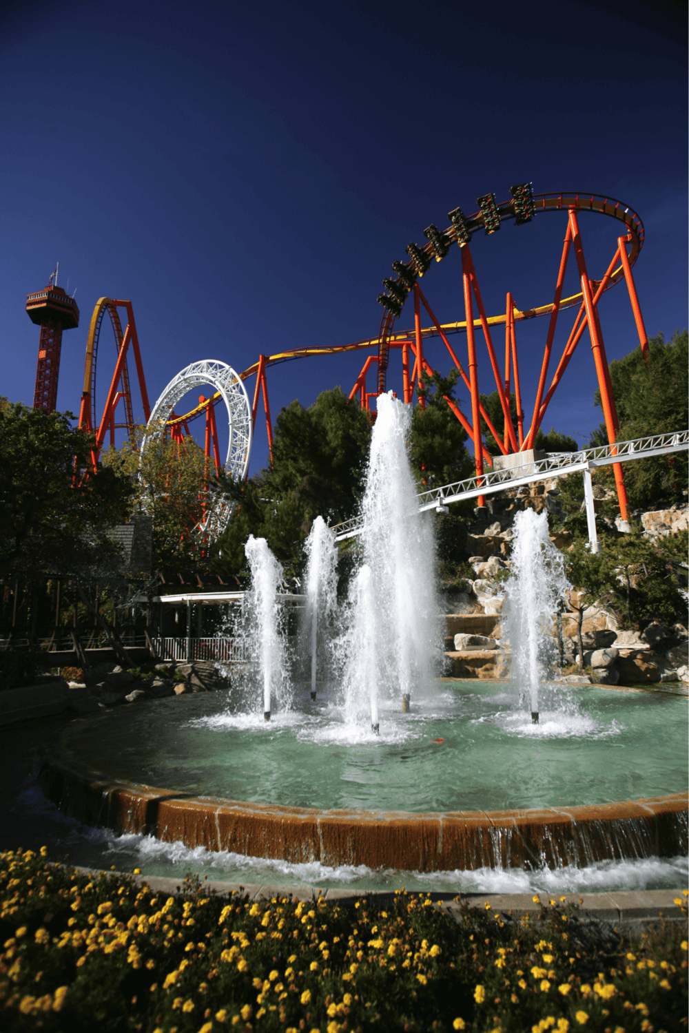Thrilling roller coaster ride at Quest for Directions amusement park with water fountain attraction.