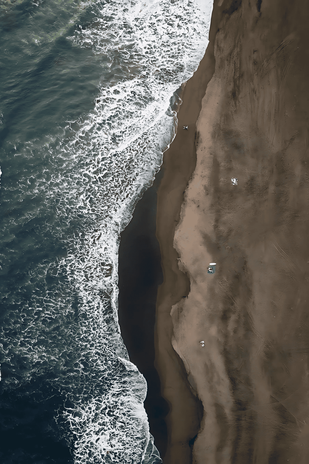 Aerial view of a sandy beach meeting the ocean with waves crashing onto the shore.