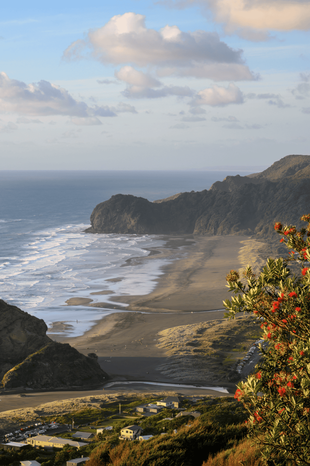 Vivid coastal landscape with sandy beach, rugged cliffs, and lush greenery during sunset.