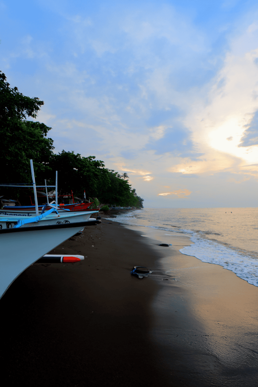Boat docked at sunset on tropical beach, serene ocean shoreline, travel, tourism, coastal scenery, vacation destination, scenic coastal view.