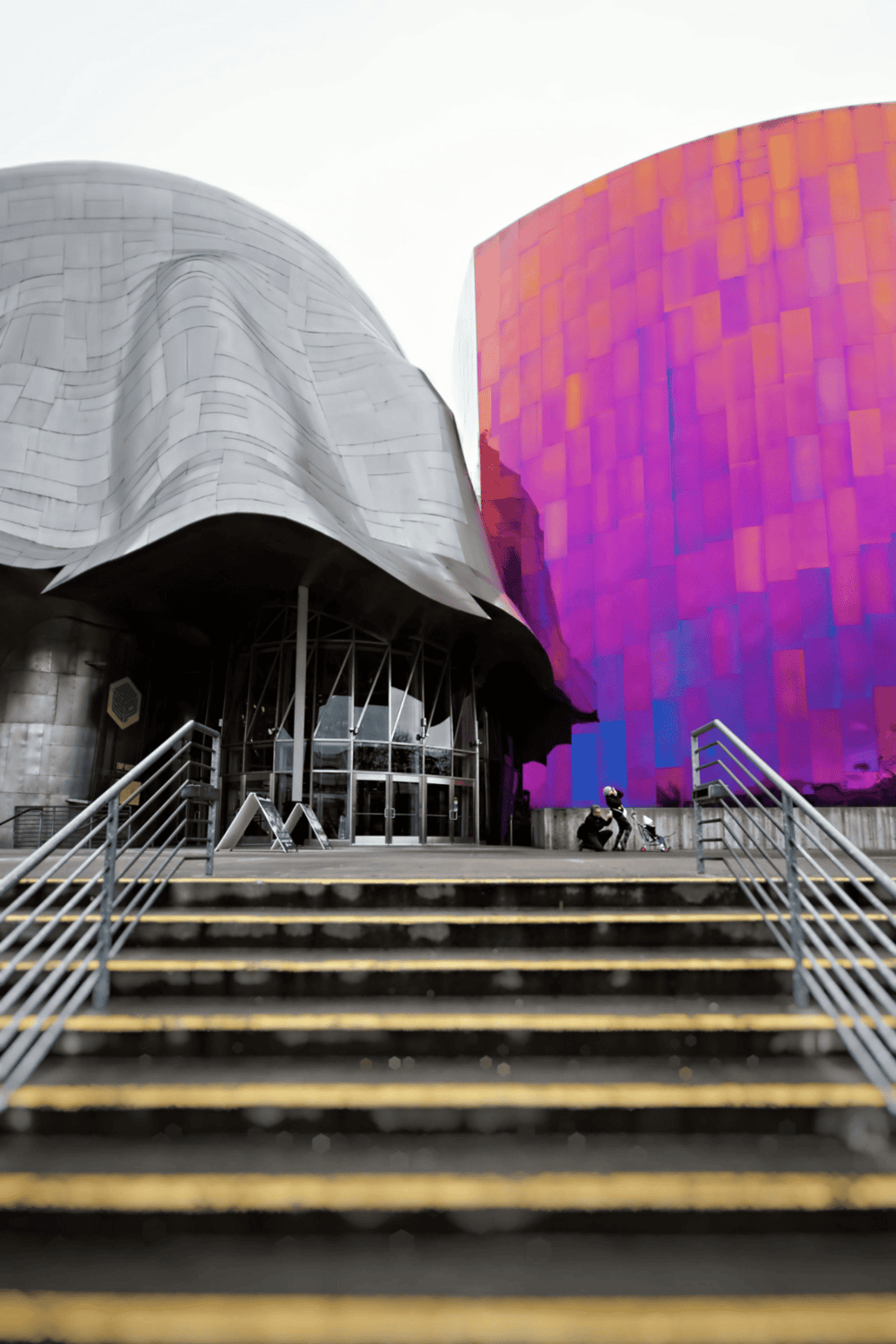 Modern architectural building with QuestForDirections signage, vibrant purple facade, and accessible stairs, ideal for navigation and directions.