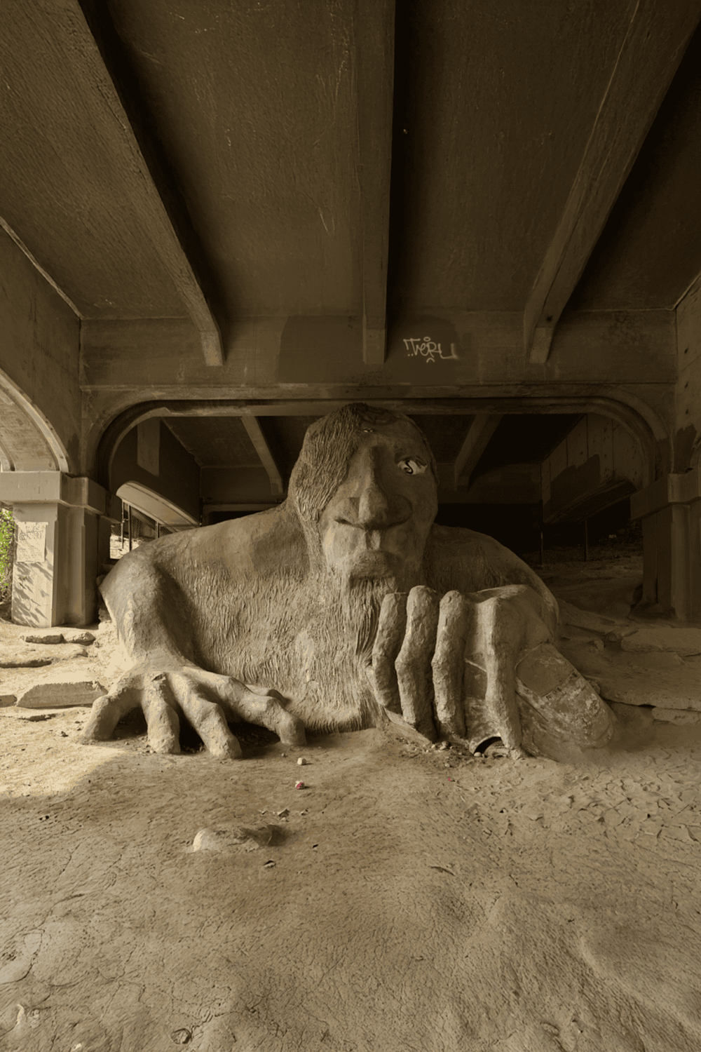 Ancient lion sculpture under a bridge, part of Quest For Directions outdoor art exhibit, showcasing wildlife artistry.
