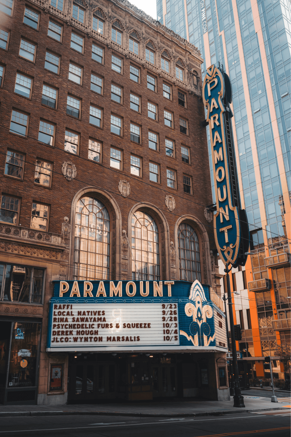 Vintage movie theater marquee at Paramount Theater in downtown cityscape with skyscrapers.