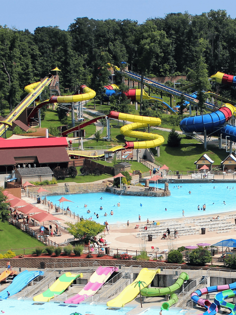 Water park with colorful slides and swimming pools in a lush green outdoor setting.