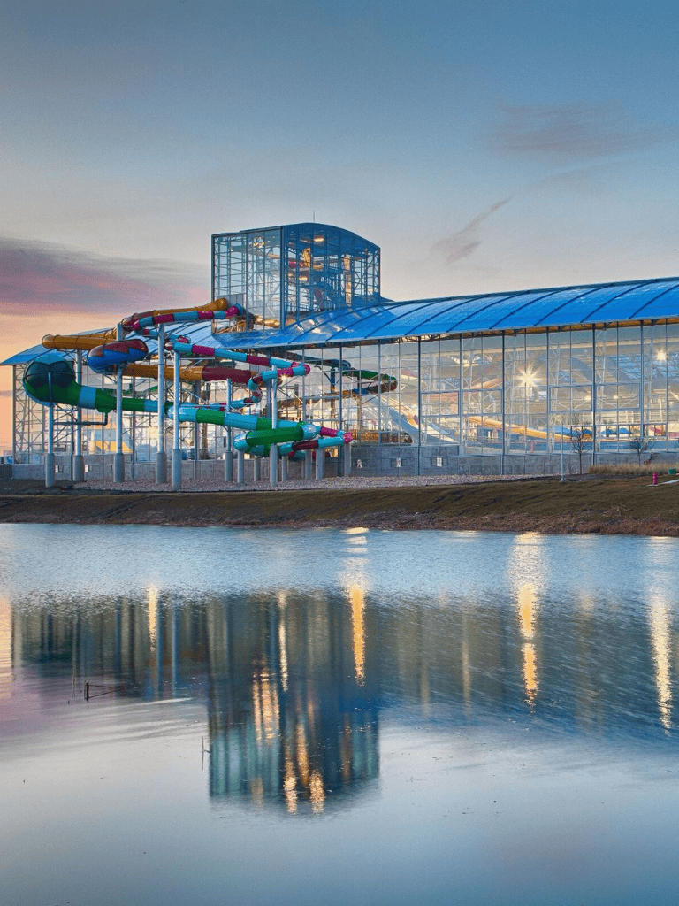 Colorful water park slides at sunset with reflections in water.