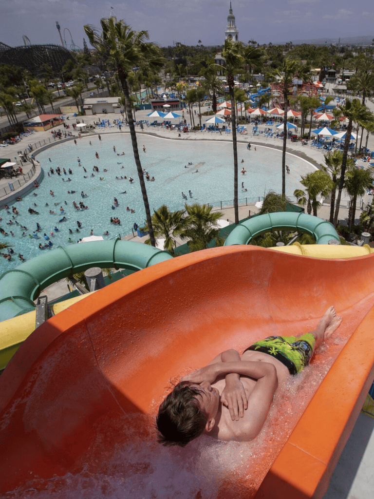 Open water slide at water park with swimming pool and kids' area, outdoor fun for families.