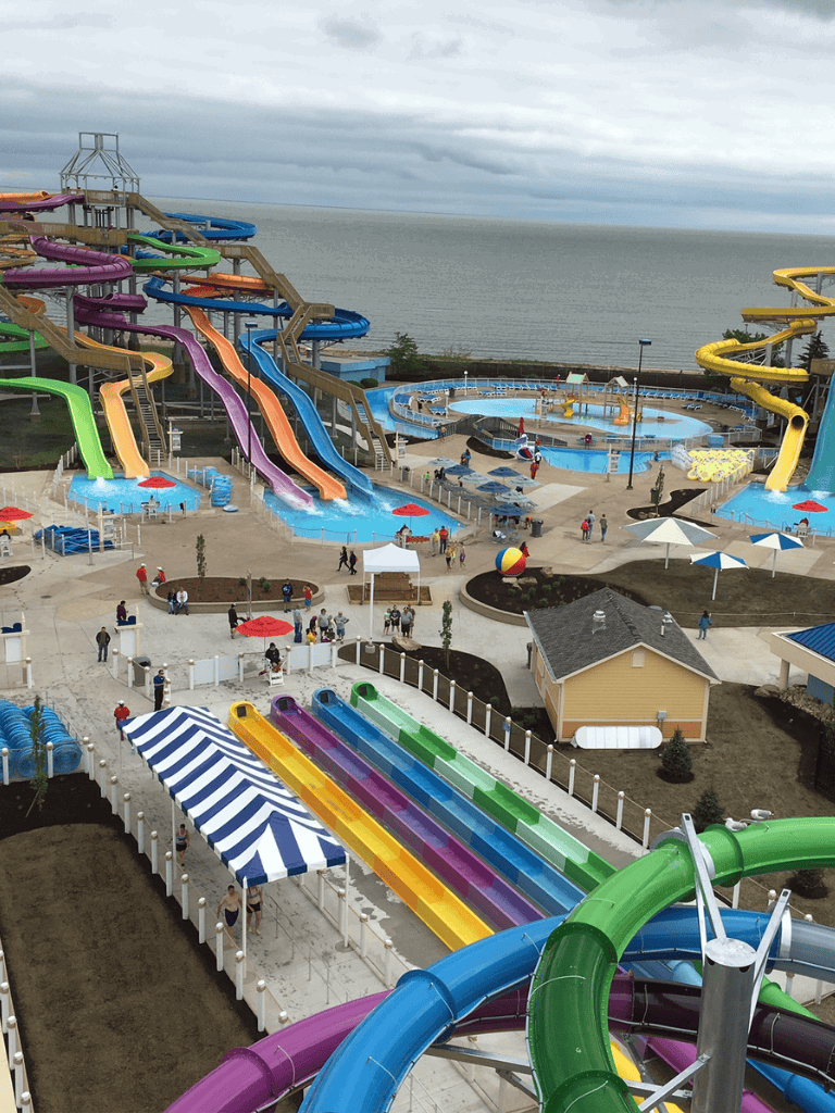 Colorful water slides and lazy river at Quest for Directions waterpark, ocean view in background.