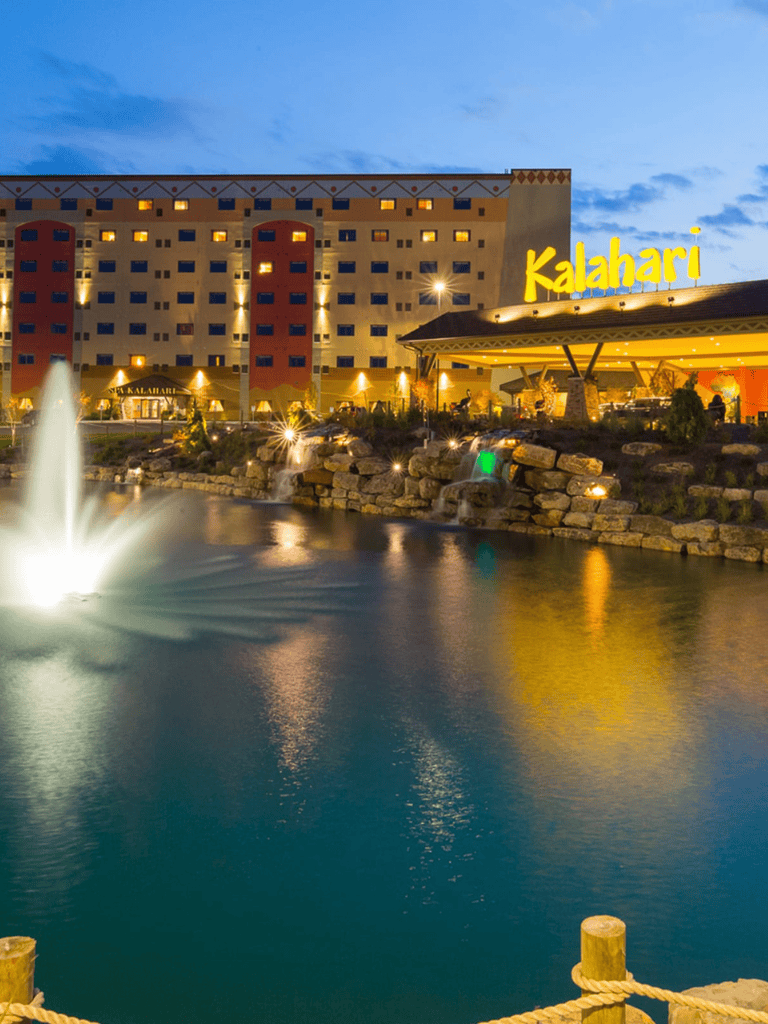 Colorful Kalahari Resort hotel exterior with water fountain and landscape at dusk, great for family vacations.