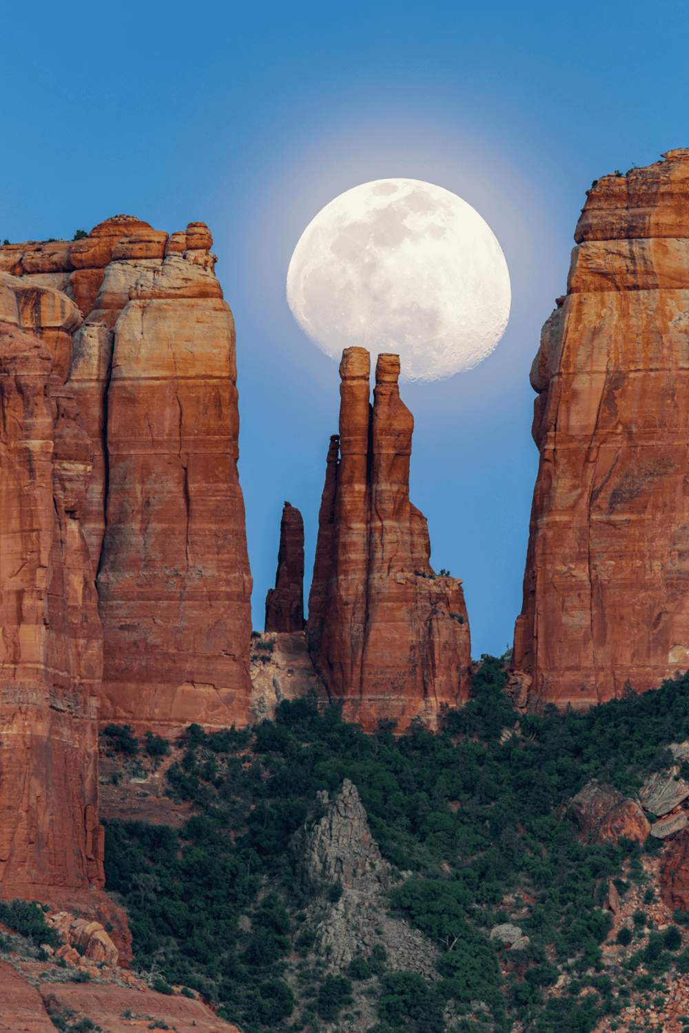 Vast desert rocks with full moon over red canyon landscape at dusk.