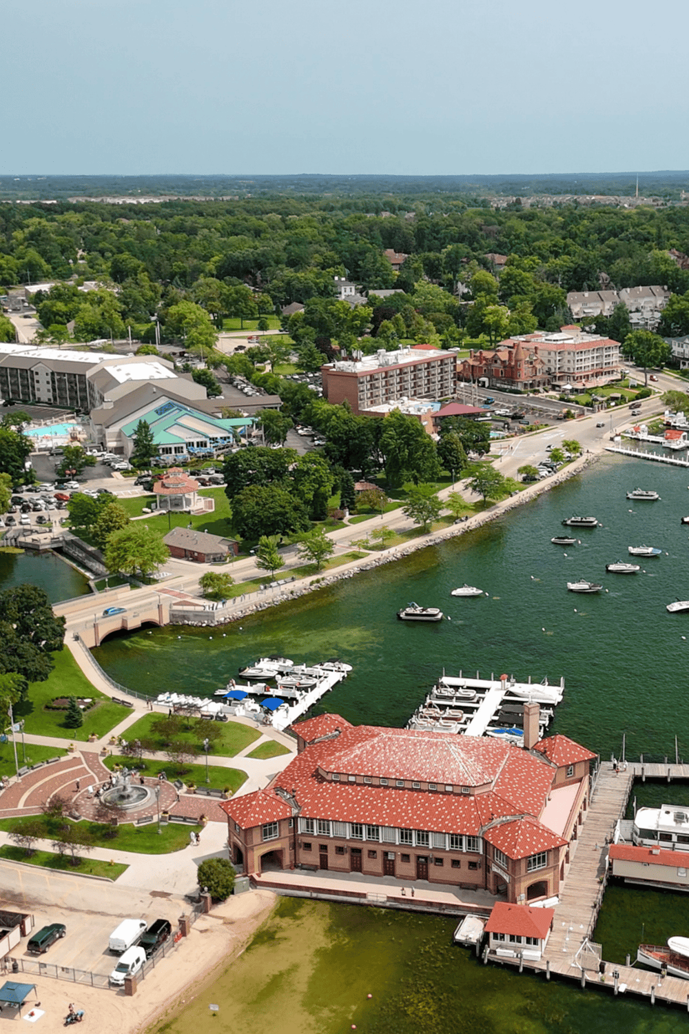 Aerial view of lakeside hotel and marina with boats, lush greenery, and surrounding residential area, in QuestForDirections location.