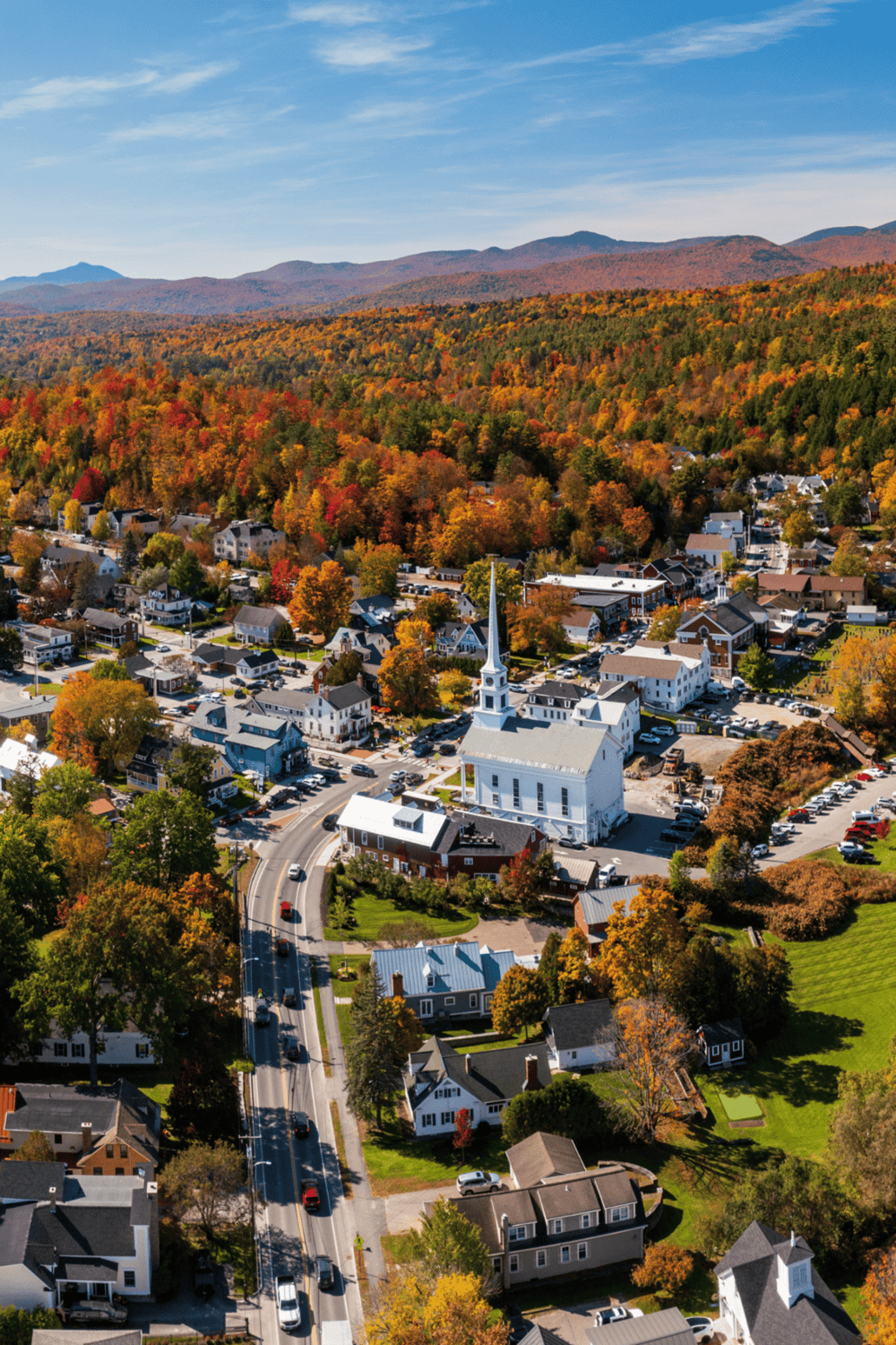 Scenic autumn town with church and colorful fall foliage in a mountain setting.