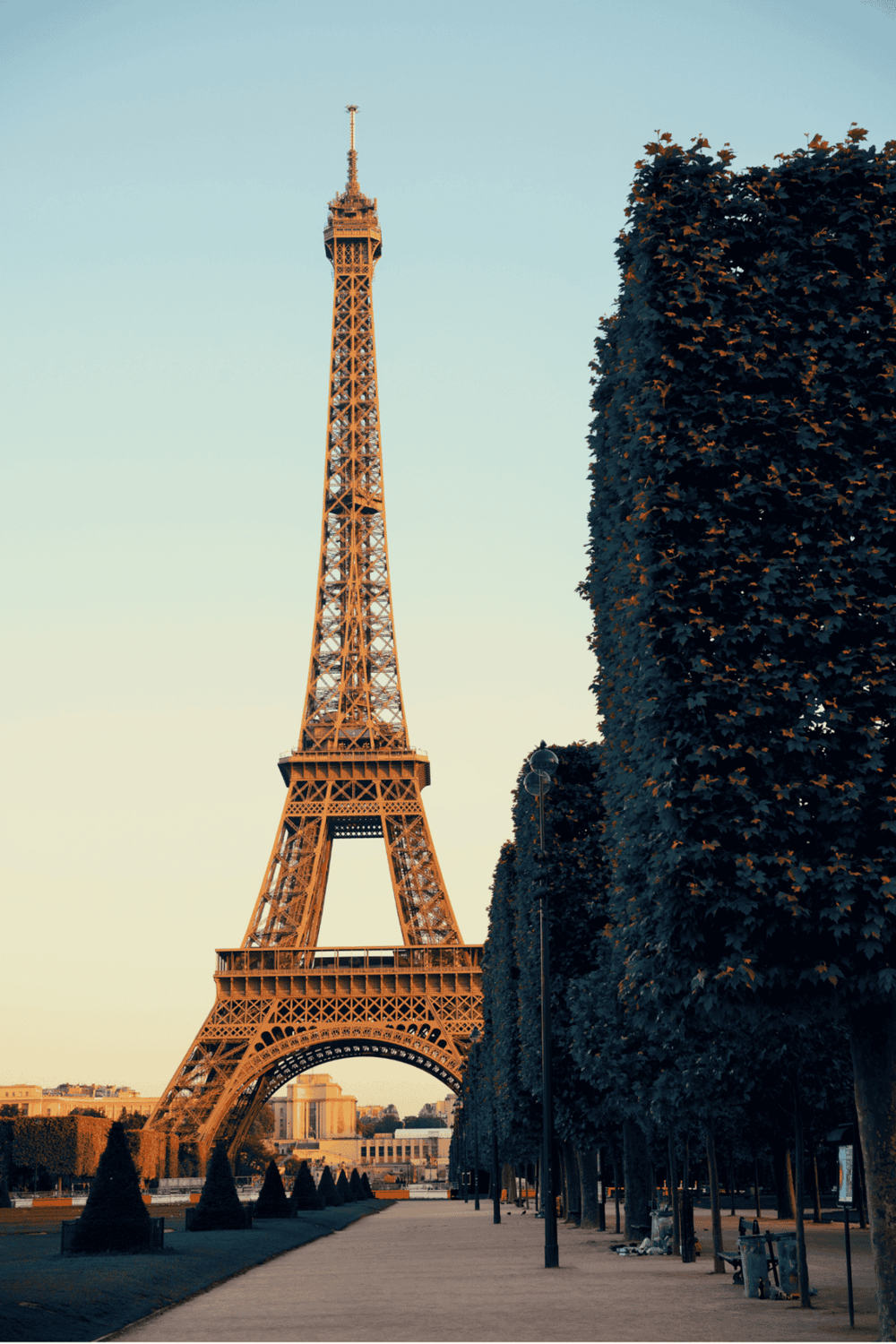 Eiffel Tower in Paris with scenic pathway and trees, famous French landmark and travel destination.