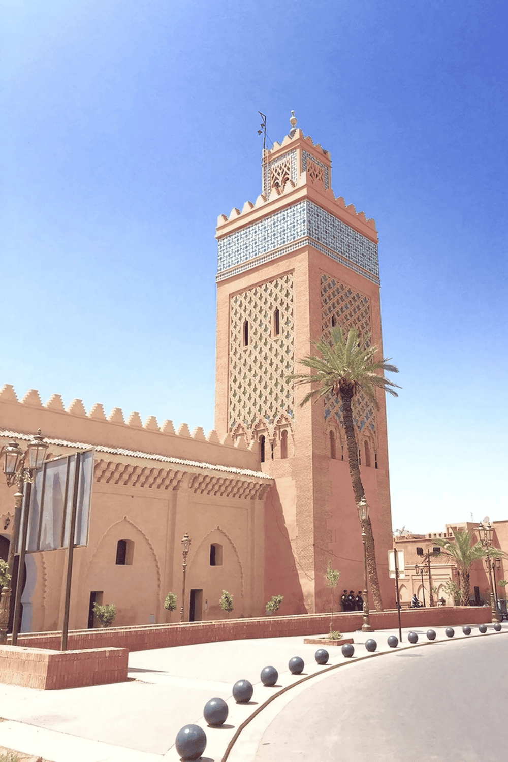 Colorful Moroccan minaret with traditional architecture and desert landscape.