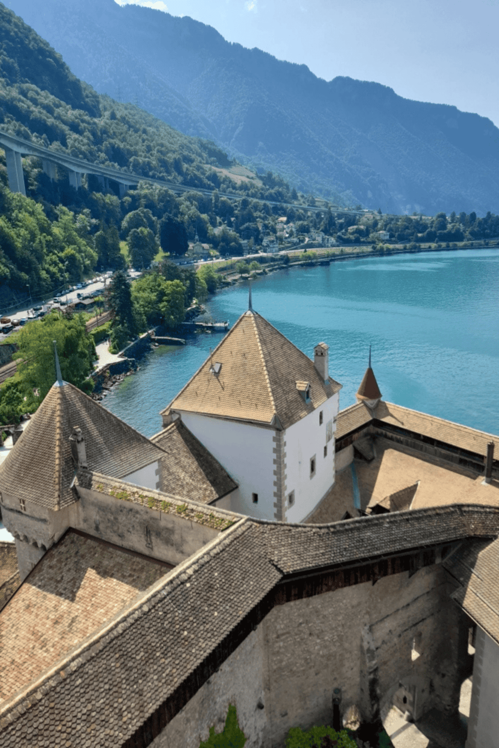 Serene lakeside view of a historic castle with mountains in the background, highlighting travel, tourism, and scenic destinations.