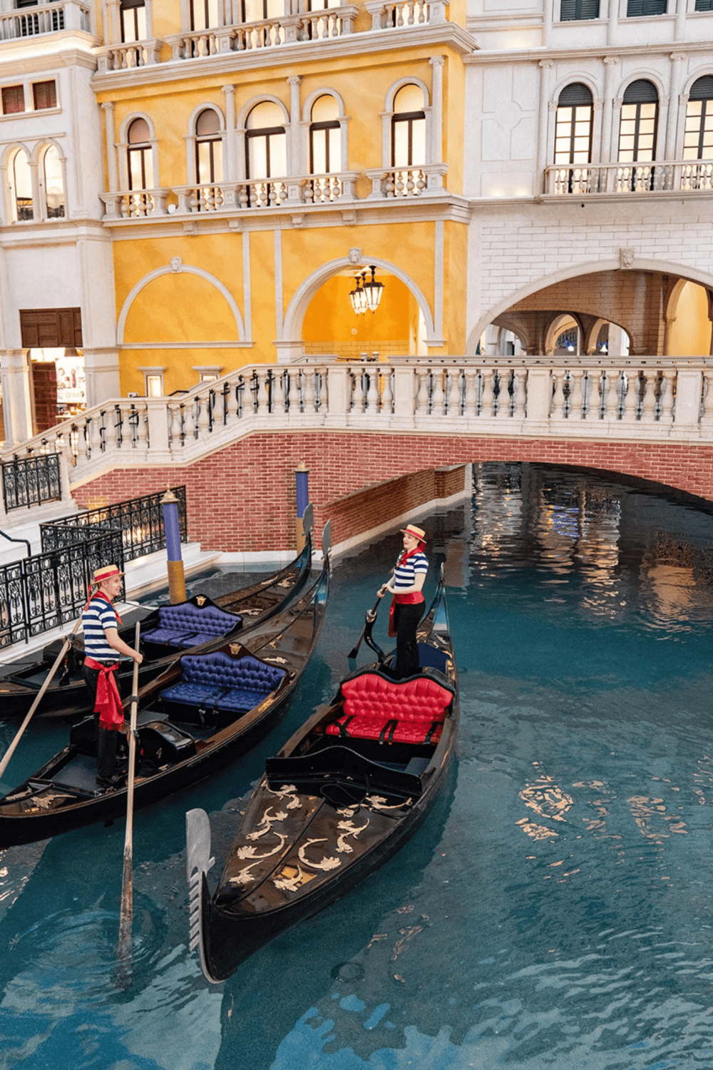 Gondolas floating in indoor canal at QuestForDirections hotel with European-inspired architecture.