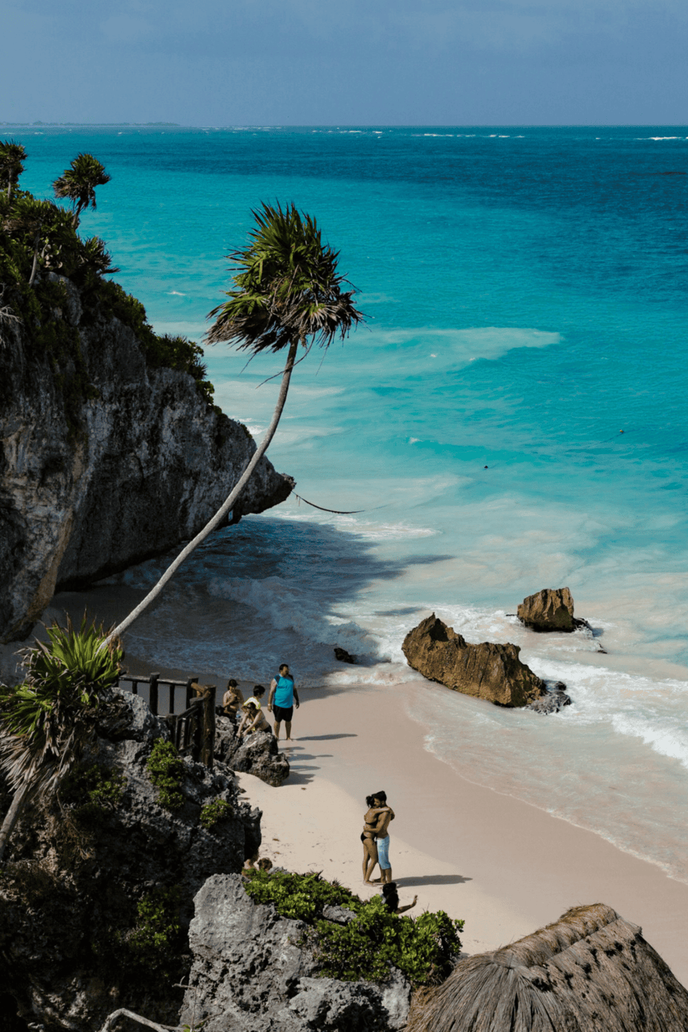 Secluded tropical beach with turquoise waters, rocky cliffs, and palm trees, perfect for relaxation and scenic views.