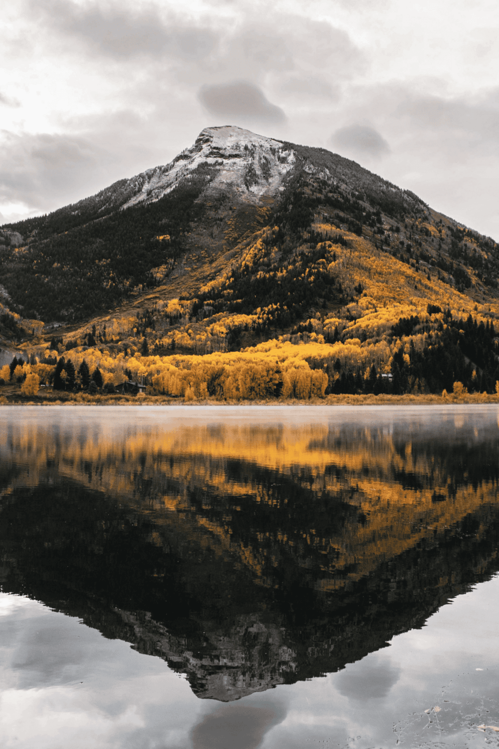Serene mountain lake with autumn foliage and reflection, ideal for nature travel and outdoor adventures.