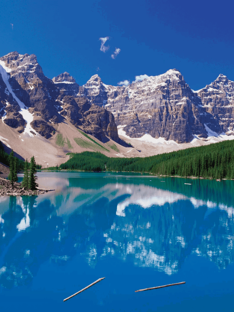 Serene mountain lake reflecting rocky peaks and blue sky, scenic outdoor landscape.