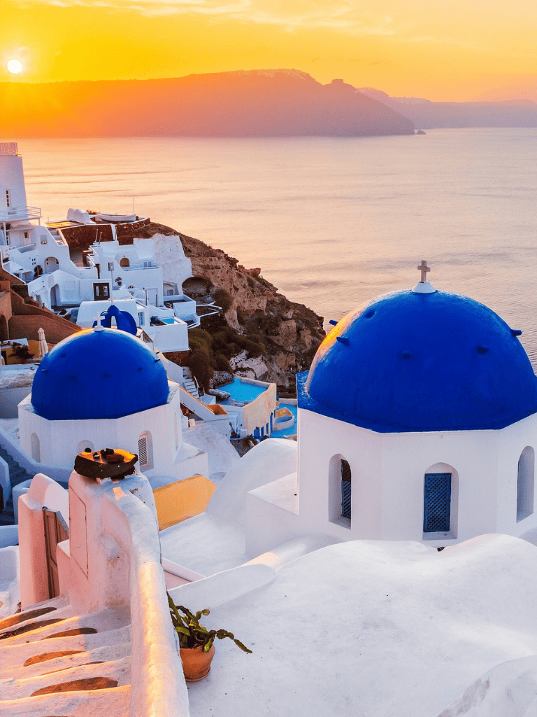 Colorful Santorini sunset over iconic blue-domed churches and white architecture, Greece travel destination, scenic island views.