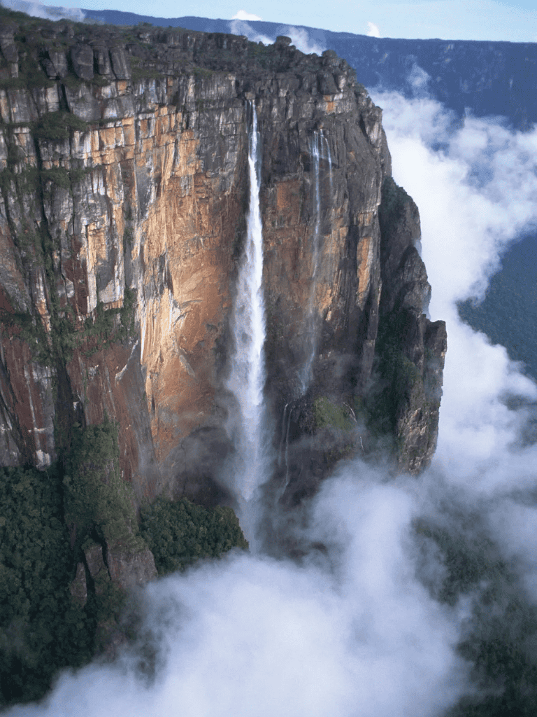 Majestic waterfall cascading down cliffs in a mountain landscape.