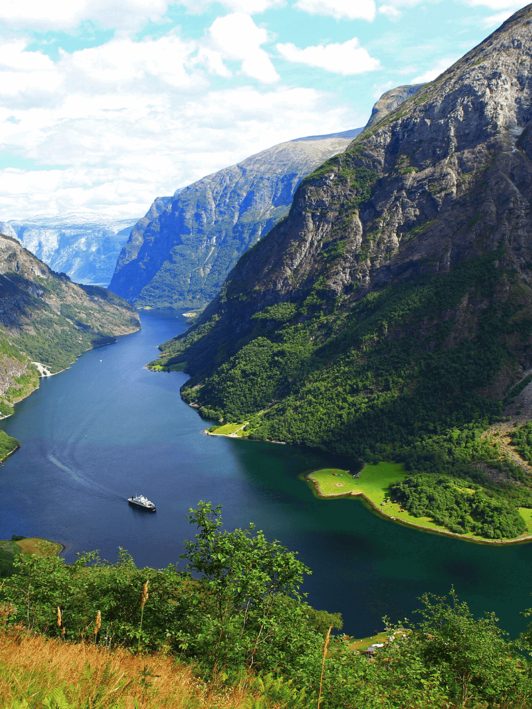 Serene fjord landscape with mountains, lush greenery, and a boat on calm waters, scenic view from QuestForDirections.