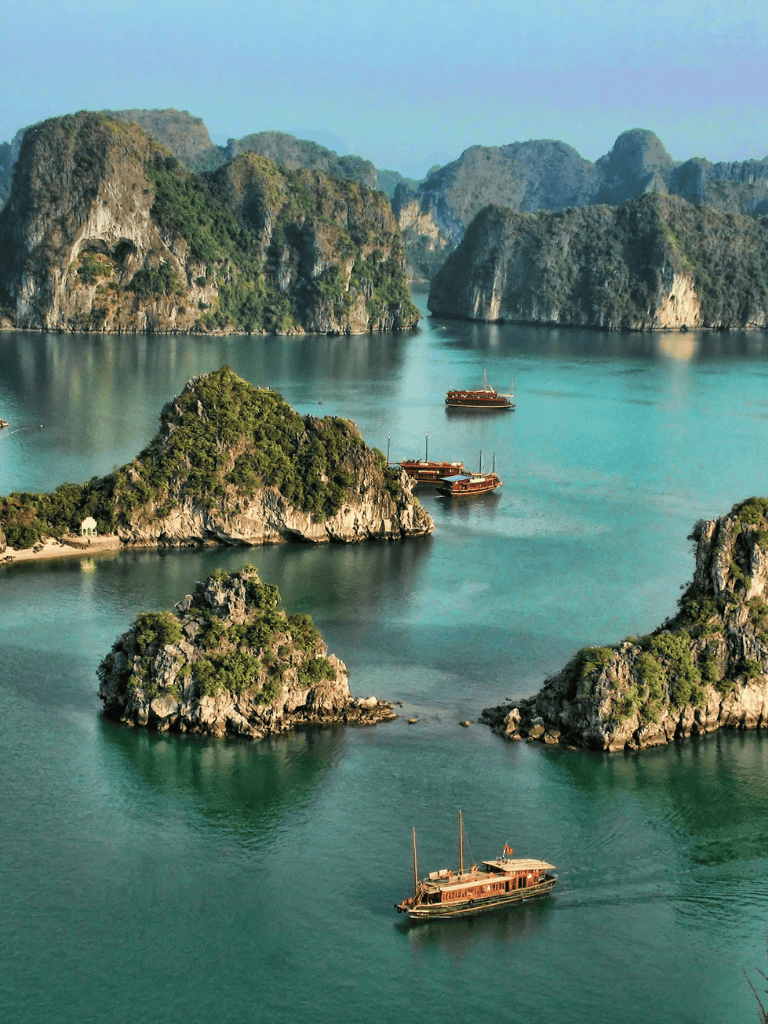Vivid photo of limestone islands and traditional boats in Ha Long Bay, Vietnam.