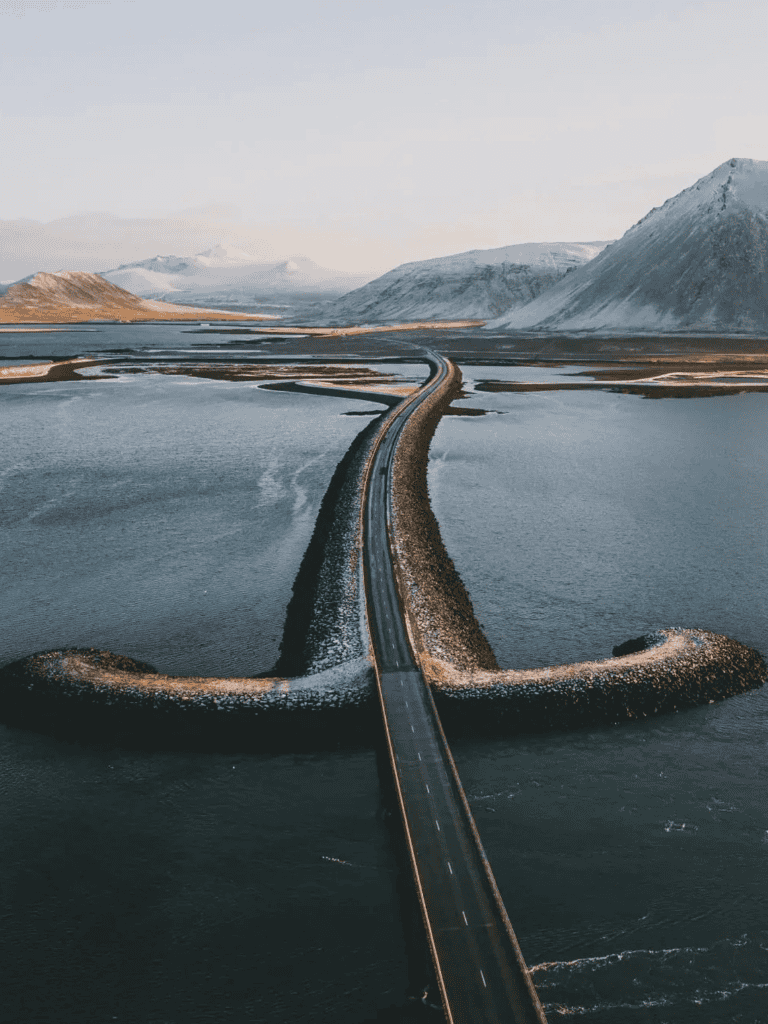Scenic bridge over water with mountain backdrop in Iceland.