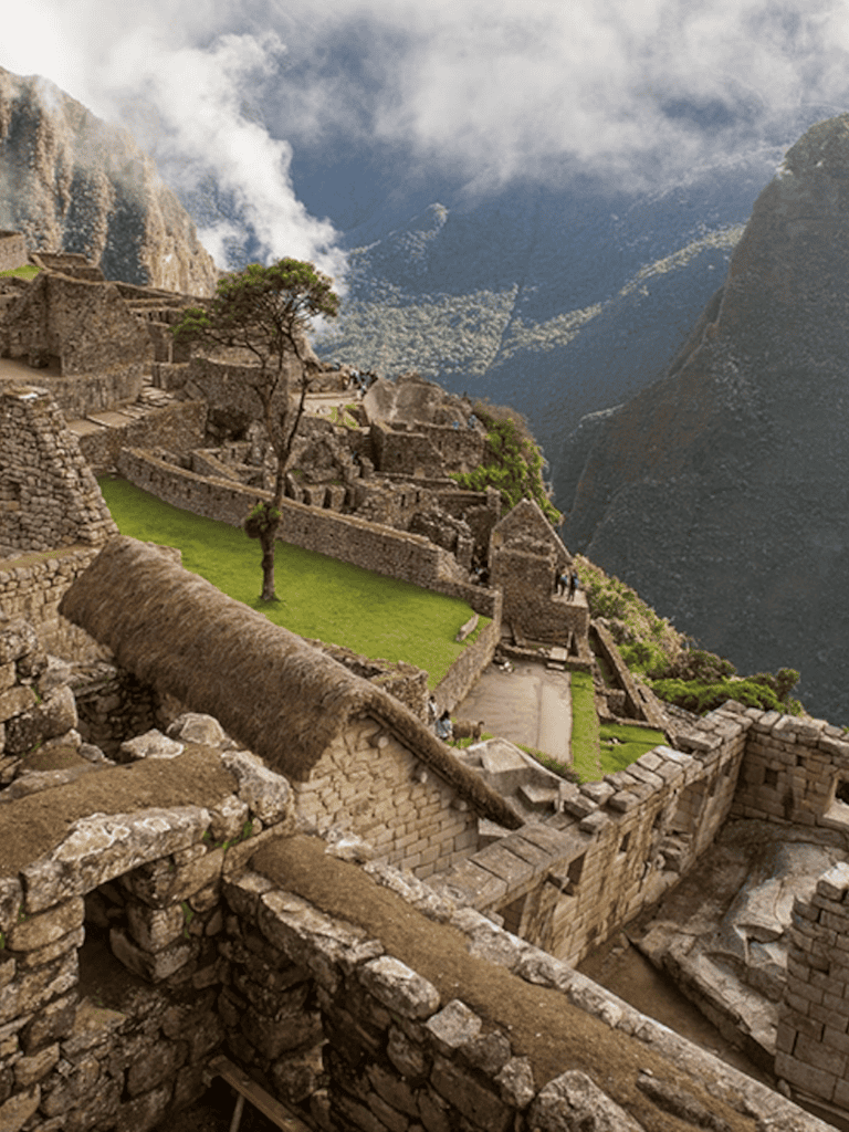 Ancient Machu Picchu ruins in the Andes mountain, Peru, with stone terraces and misty sky.