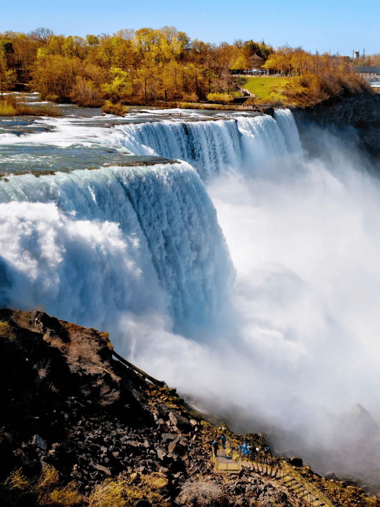 Majestic Niagara Falls with cascading water and autumn foliage, popular tourist attraction in North America.