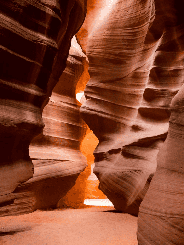 Vast sandstone canyon with winding walls, sunlight filtering through, popular for adventure and nature travel.