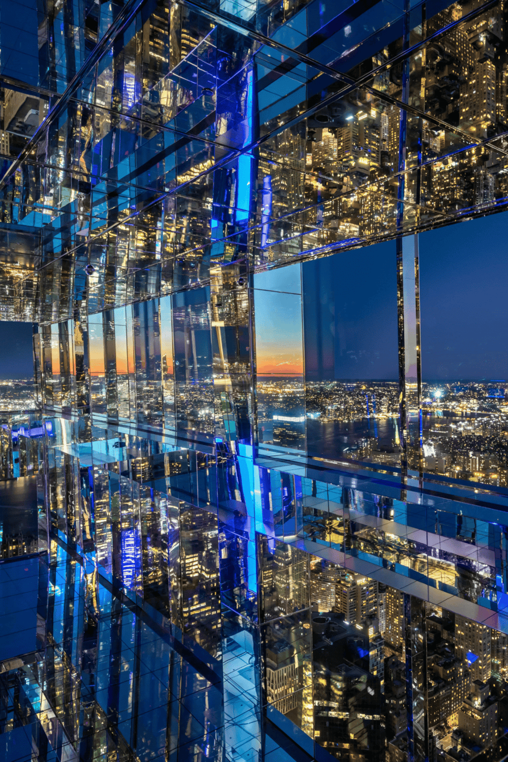 Stunning city skyline view through reflective glass building at sunset.