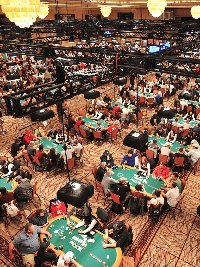 Bright casino tournament with players playing poker at tables, stage lighting, and casino atmosphere.