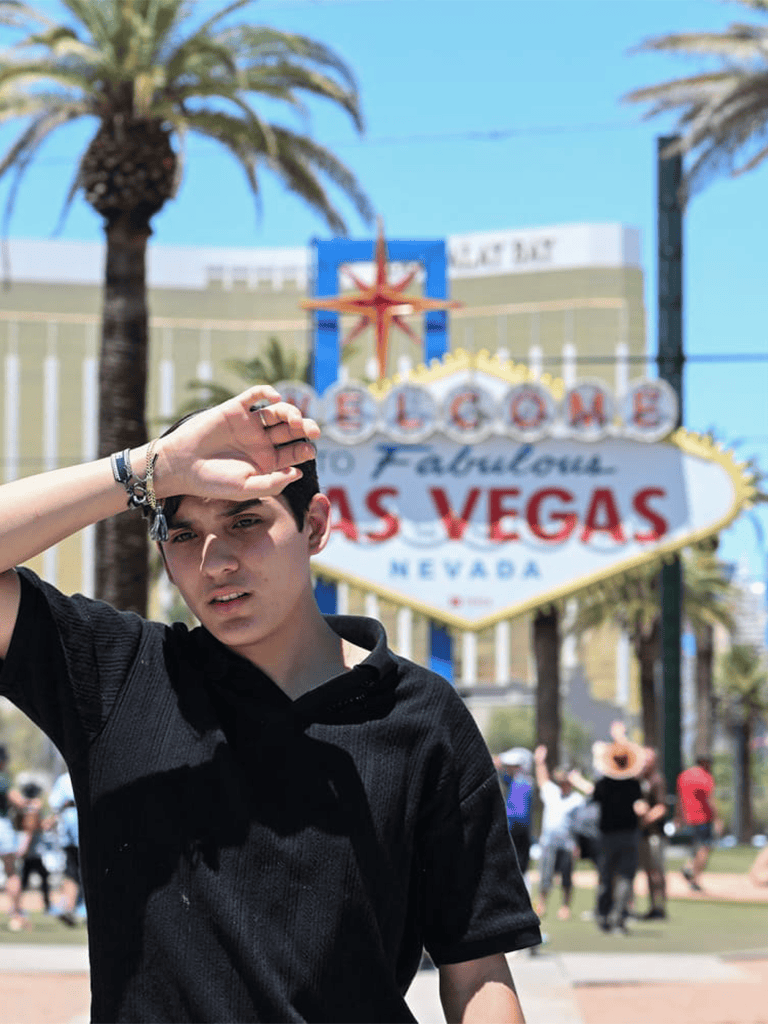 Bright young man posing in front of the iconic Las Vegas Welcome Sign, capturing the excitement of a Vegas trip.