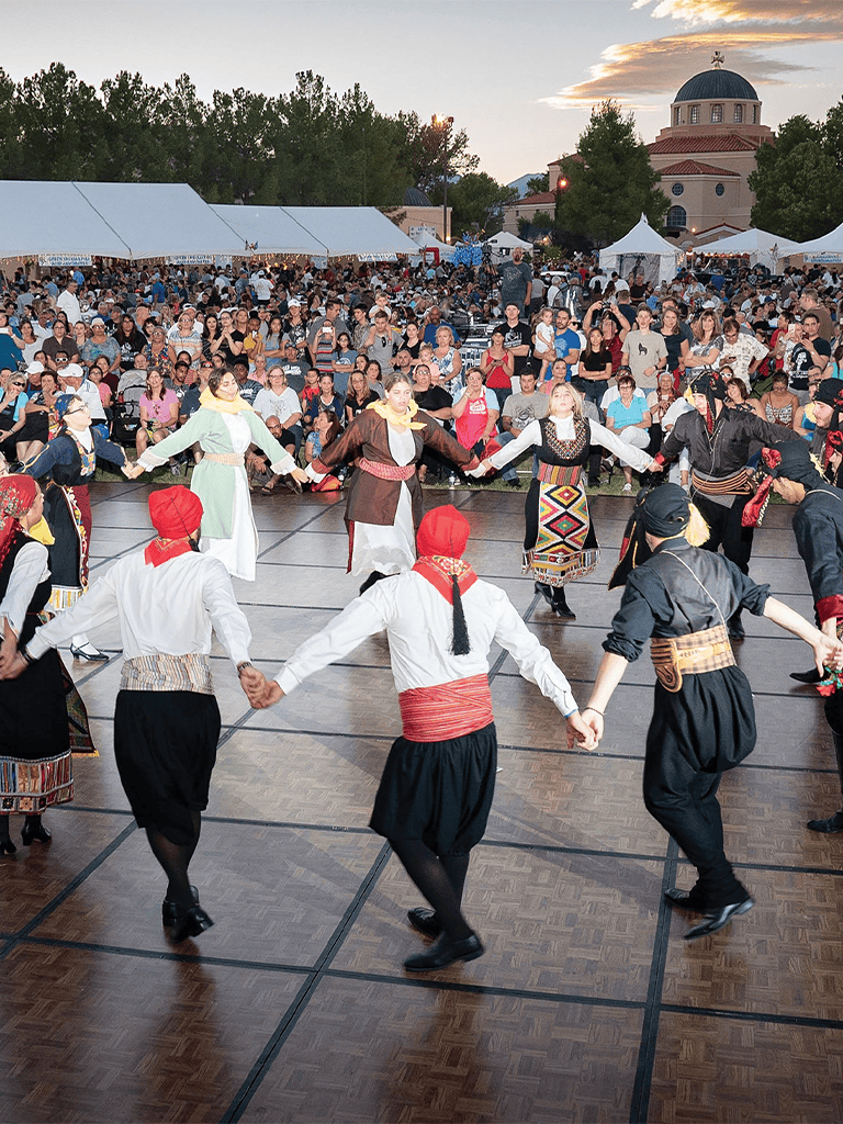 Traditional Greek dance performance at QuestForDirections cultural event, showcasing vibrant costumes and lively music.