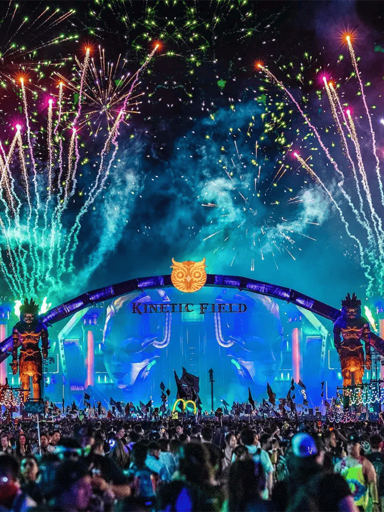 Vibrant fireworks display at Quest for Directions event with energetic crowd at Kinetic Field, dynamic DJ performance, and colorful lights.