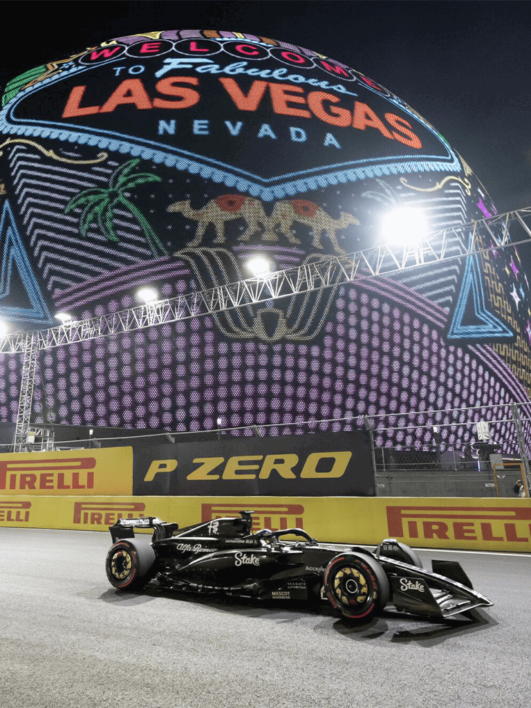 Bright Neon Las Vegas Welcome Sign with Formula 1 Race Car at Night.