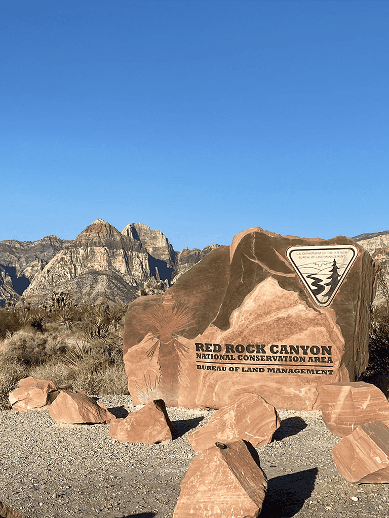 U.S. Department of the Interior Red Rock Canyon National Conservation Area sign in desert landscape.